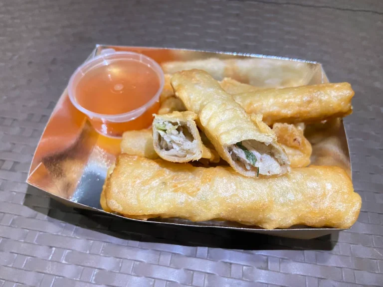 Crispy fried ngoiong served with dipping sauce on a wooden plate.